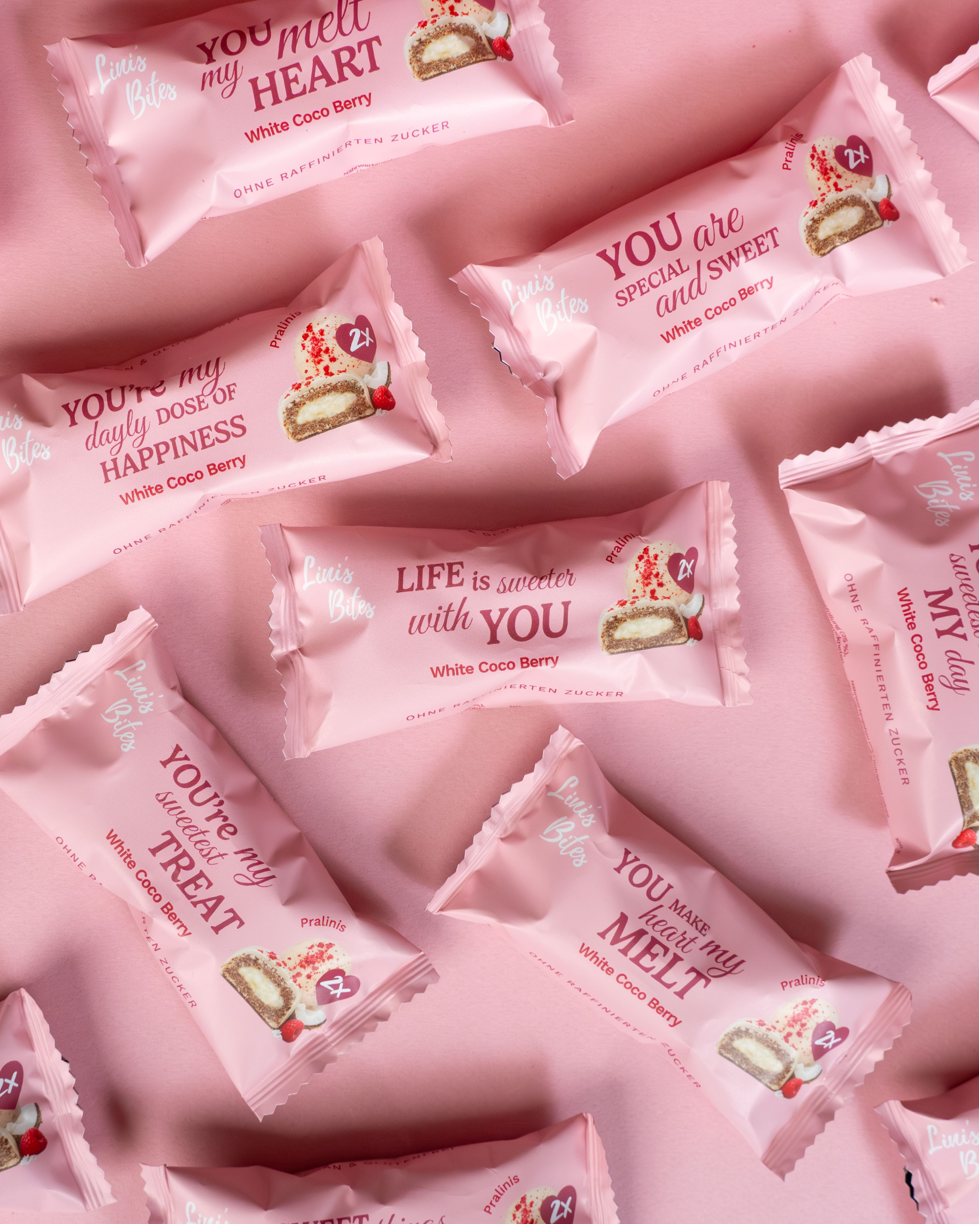 Weiße Pralinis von Linis Bites – Energy Ball-Praline Hybrid, Sorte White Coco Berry – Ansicht mehrerer verpackter Pralinis als Flatlay